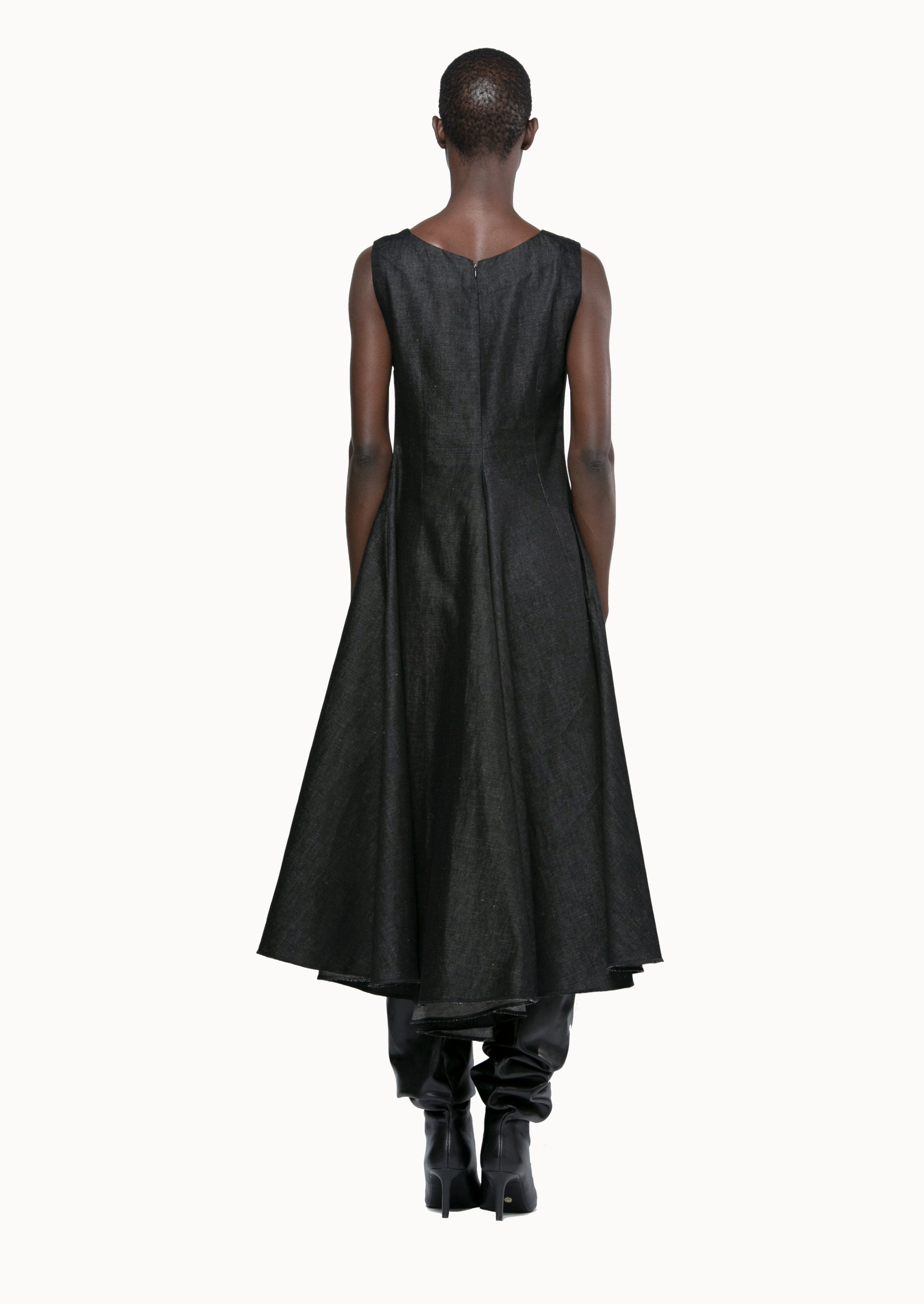 Person wearing a black sleeveless dress with a plain background